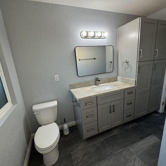 The same bathroom fully rebuilt with a new vanity, toilet, fixtures, and tile floor by M. Fitts Construction