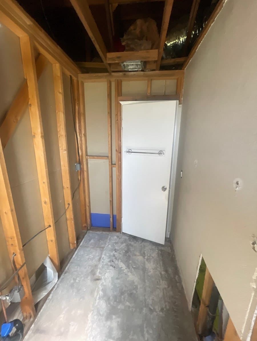 Riverside-area bathroom stripped to the studs and subfloor after a water loss, before M. Fitts Construction rebuilt it